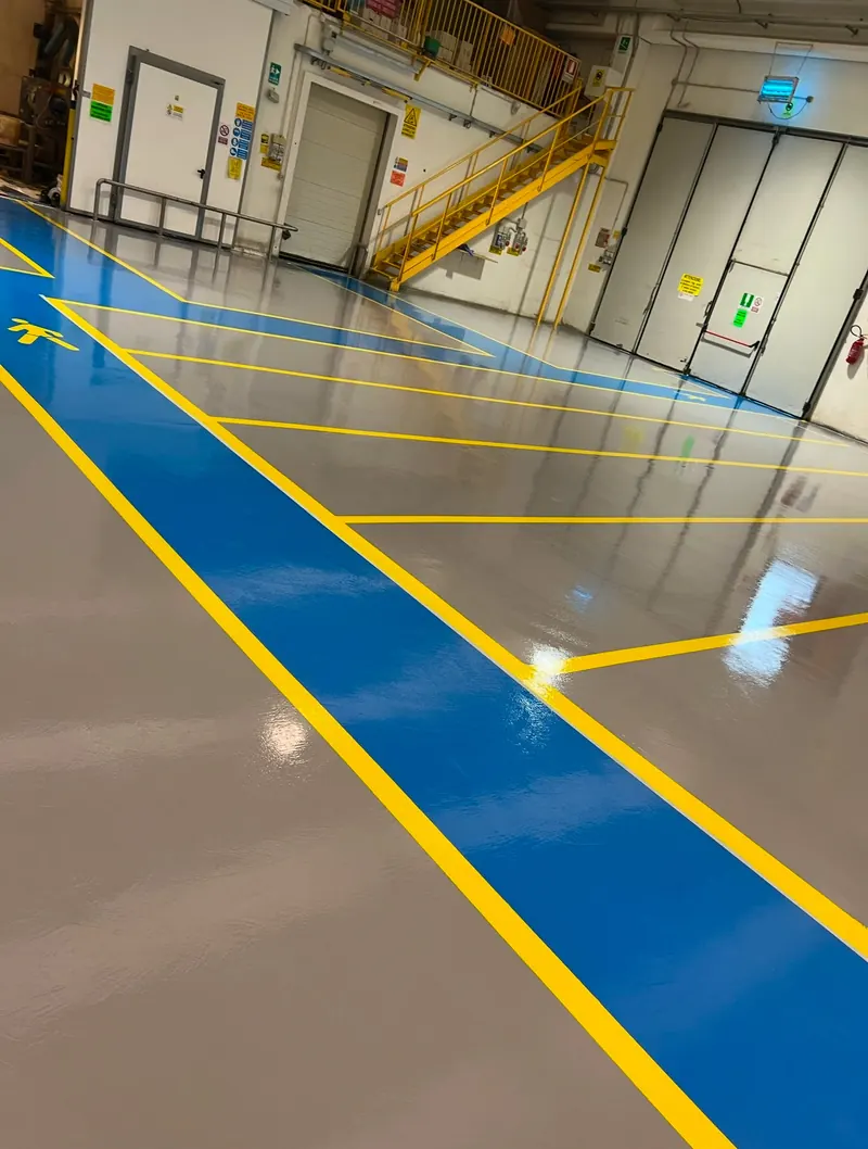 Pavimento industriale grigio con percorso pedonale azzurro