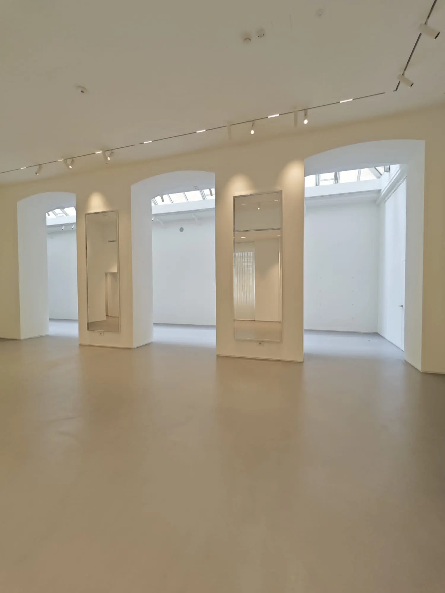 Rivestimento continuo in resina in uno spazio espositivo con archi